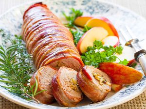 bacon wrapped pork loin served on platter with apples