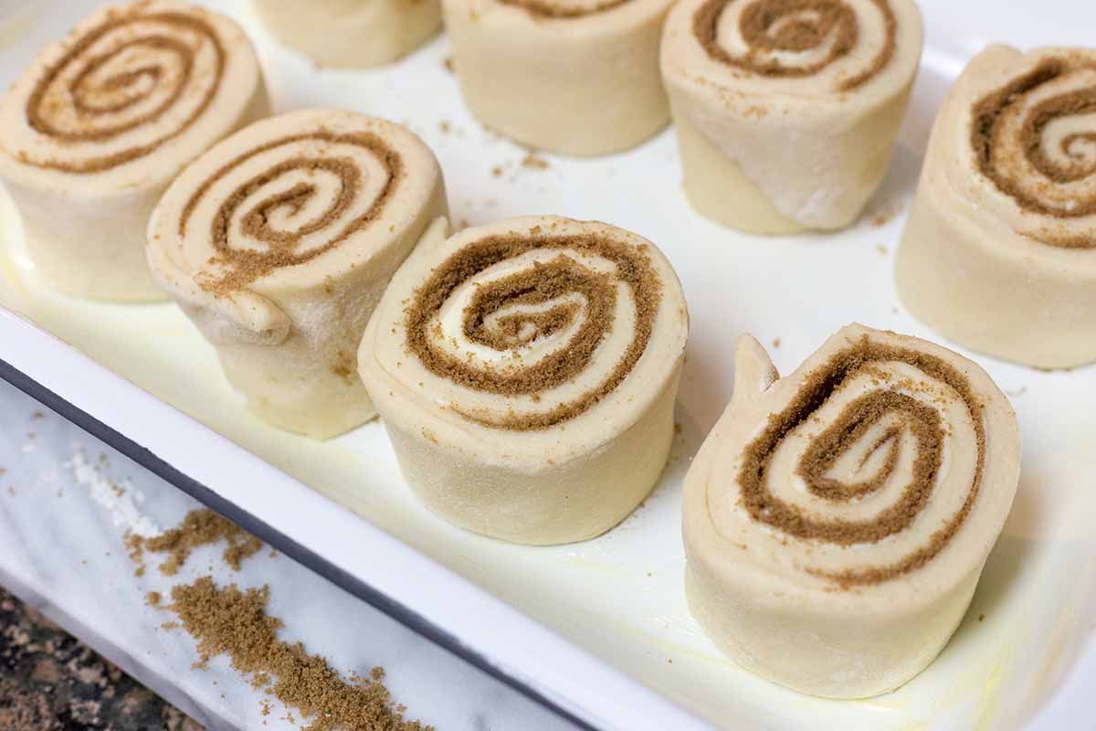 Homemade cinnamon rolls on a baking sheet covered in parchment paper.