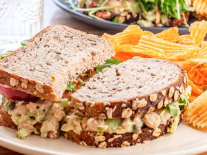 Side view of chickpea salad sandwich on a plate with chips.