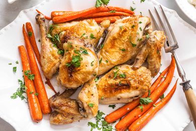Best Baked Chicken Recipe chicken on white plate with carrots and herbs