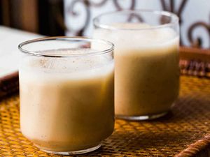 Two glasses of creamy Coquito on a woven mat