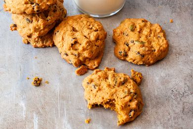 Pumpkin spice cookies stacked on a counter with a glass of milk in the background