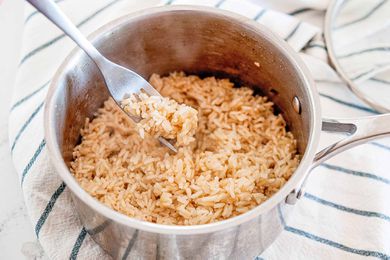 Pot with fork fluffing long grain brown rice that was cooked on a stovetop