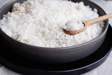 Perfect white rice in a metal pan with a wooden spoon full of cooked white rice.