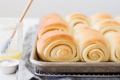 Utah's famous lion house rolls on a baking sheet with a jar of melted butter to the left.