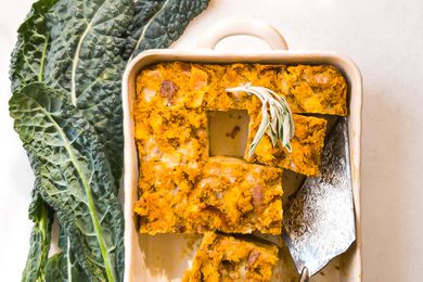 A Vegetarian Breakfast Casserole with Butternut Squash, Kale and Sage in a casserole dish with some pieces removed and a silver serving utensil in the casserole dish.