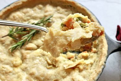 A Vegetable Casserole in a cast iron skillet with a fork scooped out.