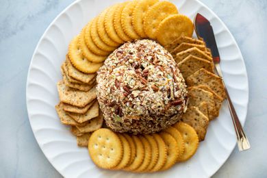 The best cheese ball is in the center of a platter and surrounded by crackers.