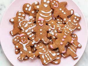 a plate piled with vegan gingerbread men and women with frosting faces and clothes