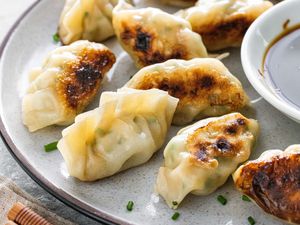 Plate of Crispy Shrimp and Chive Dumplings Garnished with Chives and Served with a Small Saucer of Soy Sauce