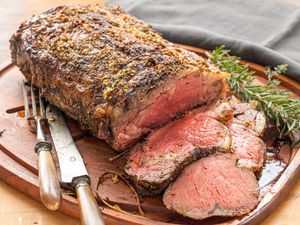 Herb butter prime rib with gravy being served on a cutting board.