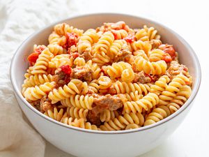 Pasta with sausage in a bowl with a white linen next to it.