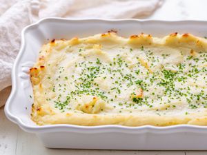 A casserole dish of make-ahead mashed potatoes with minced fresh chives on top