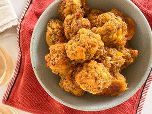 Sausage balls in a bowl at a table with glasses of wine and some table napkins