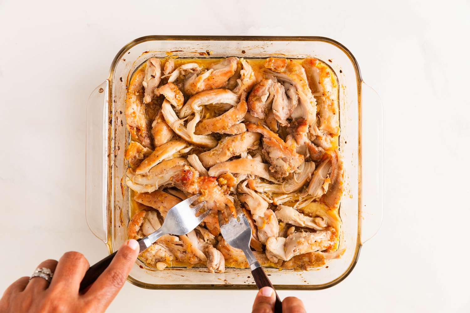 Two forks used to shred chicken thighs in the glass Pyrex dish for banh mi salad recipe 