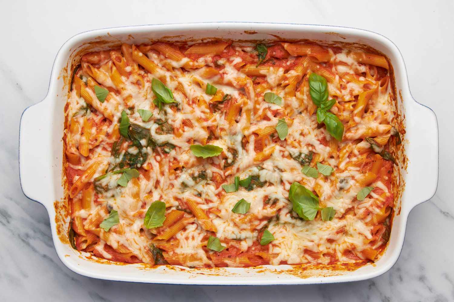 One pan baked penne alla vodka in a casserole dish topped with fresh basil 