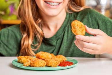 Boy eating Trader Joe's chicken nuggets with ketchup