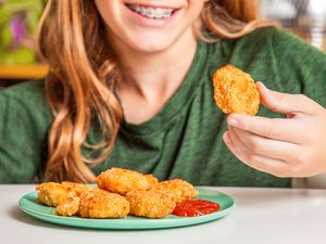 Boy eating Trader Joe's chicken nuggets with ketchup