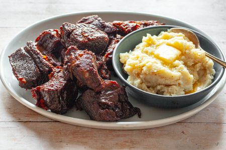 Braised Short Ribs with Root Beer BBQ Sauce on a Plate with a Bowl of Mashed Potatoes