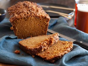 Side view of butternut quick bread with pecan streusel with slices cut in front of the loaf.