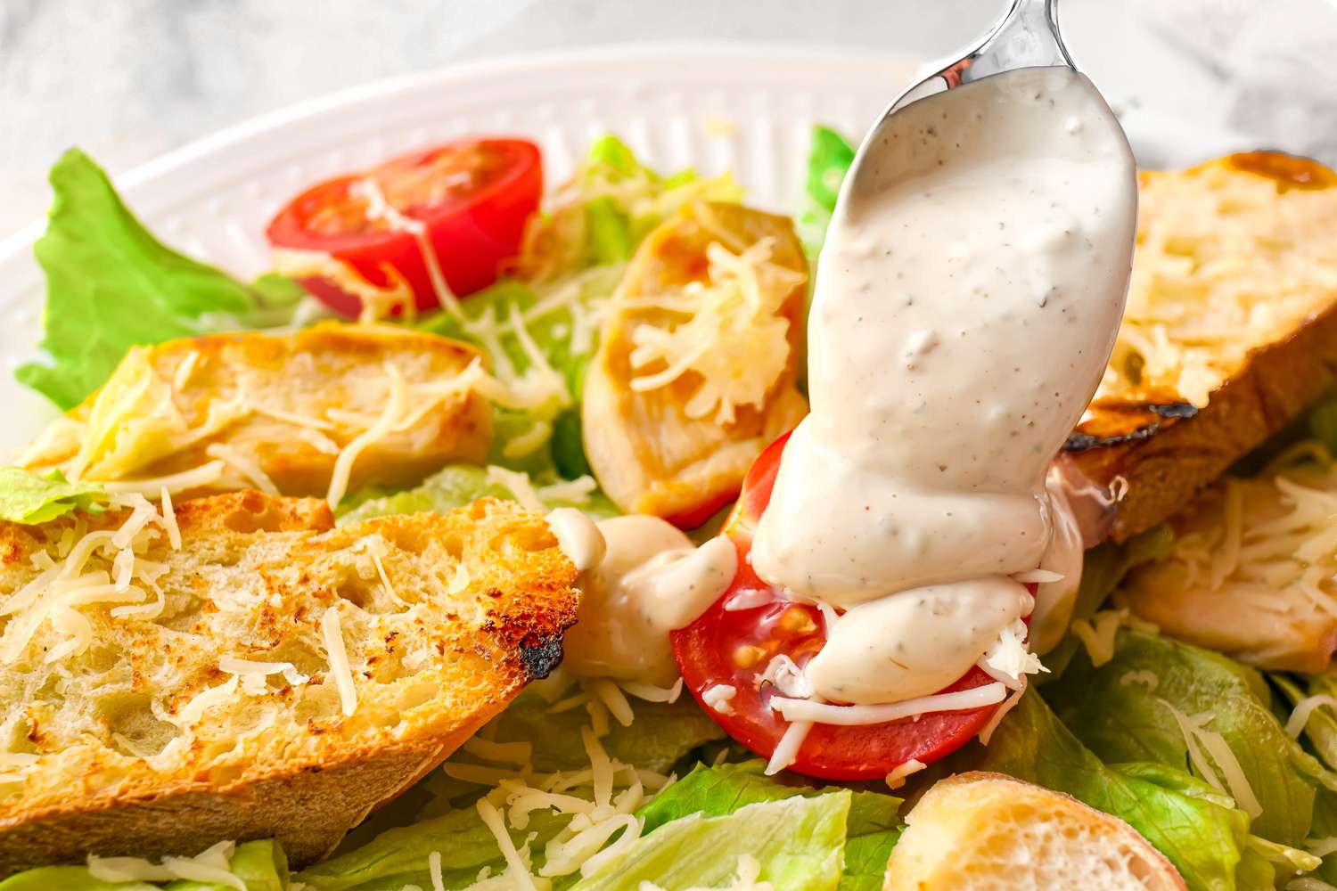 Caesar dressing spooned onto a salad 