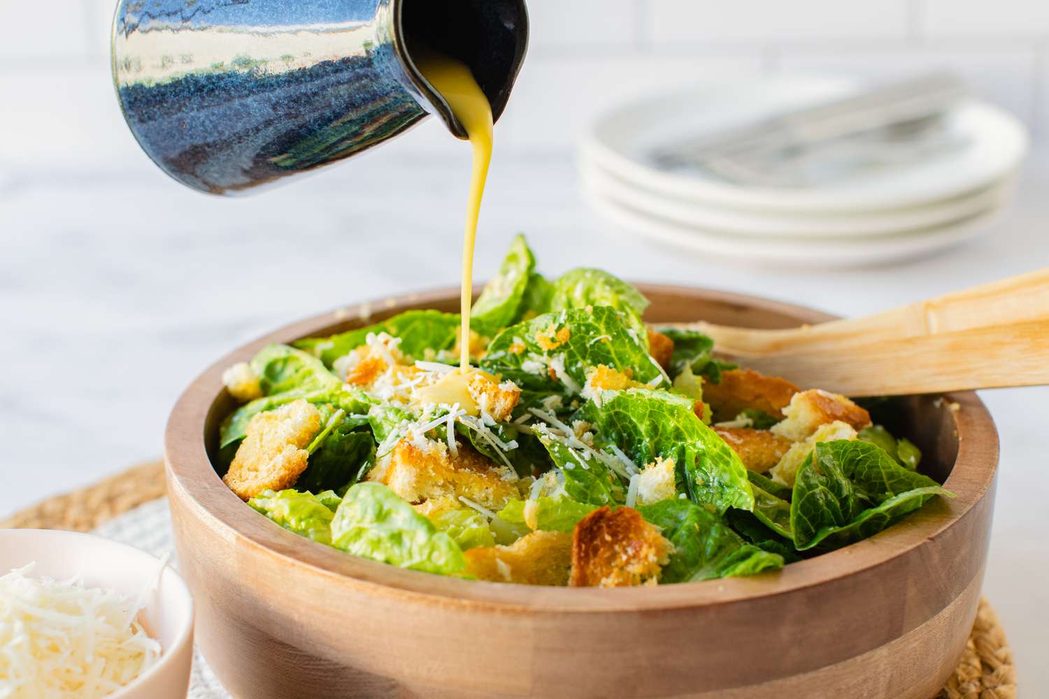 Homemade Caesar Dressing Poured into a Bowl of Classic Caesar Salad Topped with Croutons