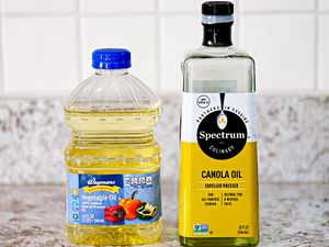 Bottle of vegetable oil on the left and a bottle of canola oil on the right (both on a counter)