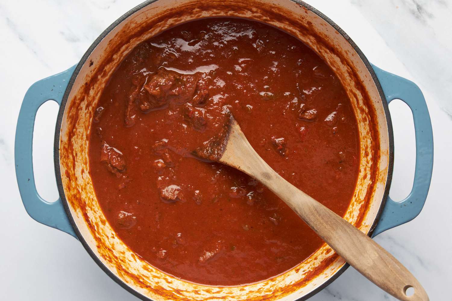 Carne picada in a Dutch oven with a wooden spoon