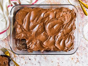 Chocolate Mayonnaise Sheet Cake in a Baking Pan, Surrounded by Small Plates, Utensils, and One Small Plate with a Slice of Cake