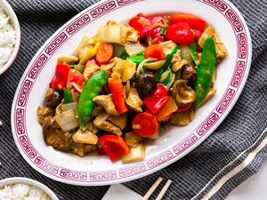 Platter of Chop Suey at a Table Setting With Chopsticks on Napkins and Bowls of Rice, All on a Grey Kitchen Towel