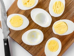 Hard boiled eggs sliced in horizontally and set on a wooden board.