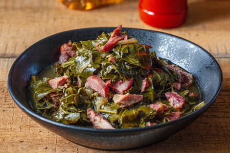 A big bowl of collard greens with pieces of ham hock