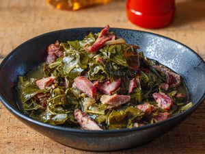A big bowl of collard greens with pieces of ham hock
