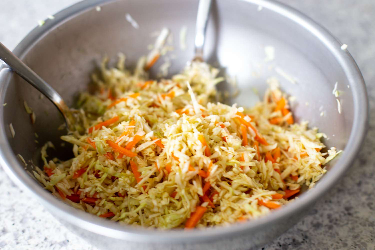 Coleslaw Tossed Together in the Bowl Using Two Forks