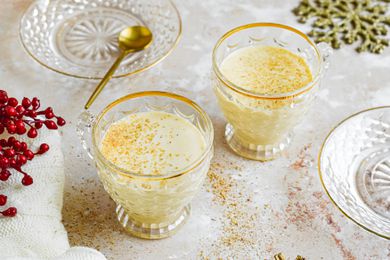 Two gold-rimmed glasses of eggnog cocktail.