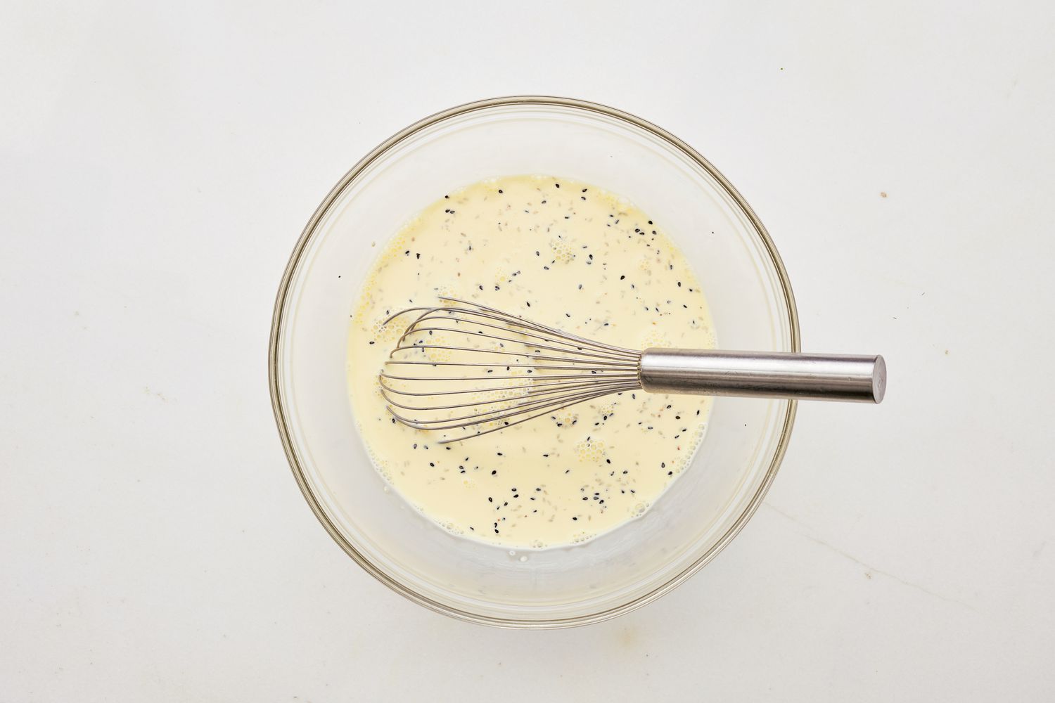 Wet ingredients for everything bagel sandwich casserole whisked together in a bowl