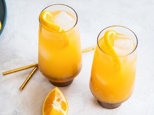 Two Glasses of Fuzzy Naval with Orange Wheels Next to an Orange Slice