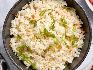 Bowl of Garlic Fried Rice (Sinangag na Kanin) next to some utensils and plates with sides