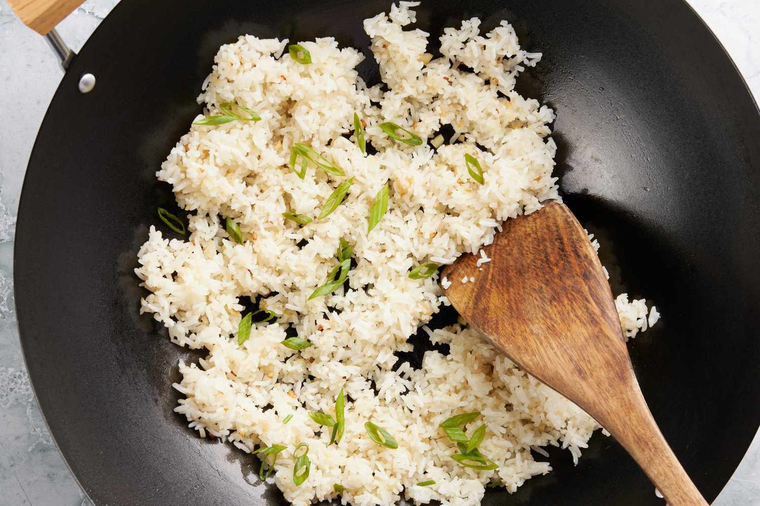 Garlic Fried Rice (Sinangag na Kanin) topped with sliced green onions in the wok