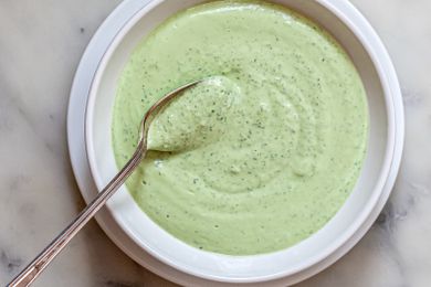 Overhead view of quick and easy green tahini sauce in a shallow bowl and a spoon.