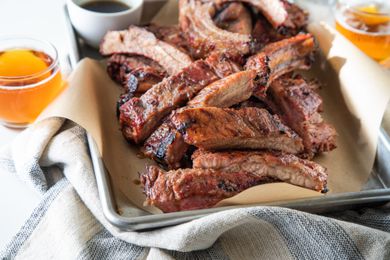 A parchment lined baking sheet with cut ribs from a grilled ribs recipe.