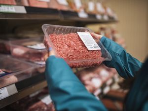 Unrecognisable woman choosing fresh ground beef in supermarket.