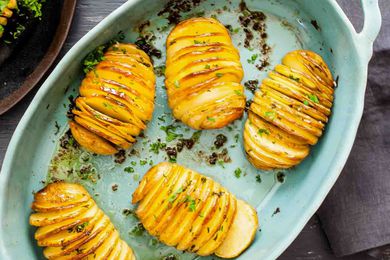 Five hasselback potatoes in a roasting dish