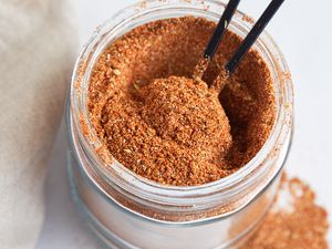 A jar of Cajun seasoning with a spoon in it