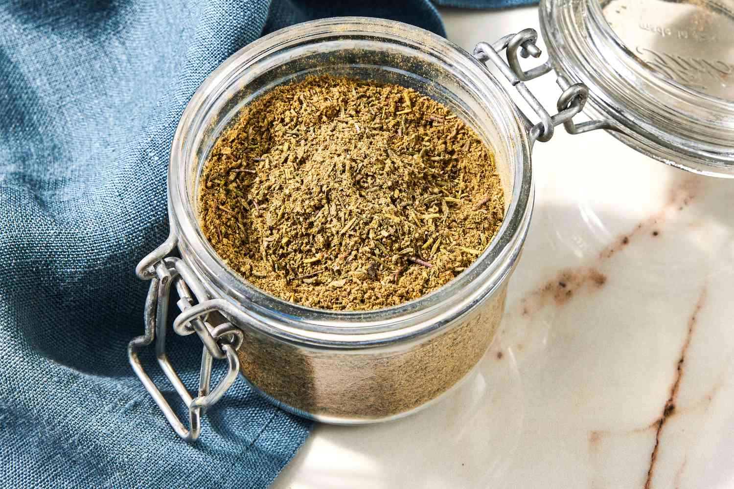 Jar of Poultry Seasoning Next to a Navy Blue Table Napkin