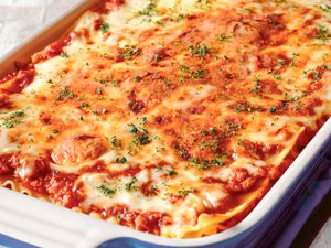 Lasagna in a casserole dish and topped with dried basil