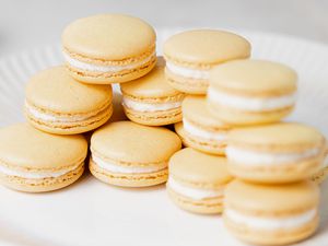 Lemon buttercream macarons set on top of each other on a plate.
