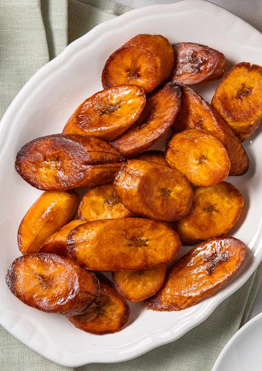 Maduros (Fried Sweet Plantains) on a Plate, and in the Surroundings, a Light Olive Green Kitchen Towel