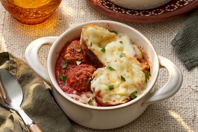 Bowl of meatball sub soup in a pot-like ramekin a rustic table setting