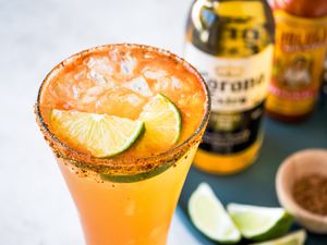 Michelada with Ingredients (Beer, Cholula, Lime Wedges, etc) in the Background